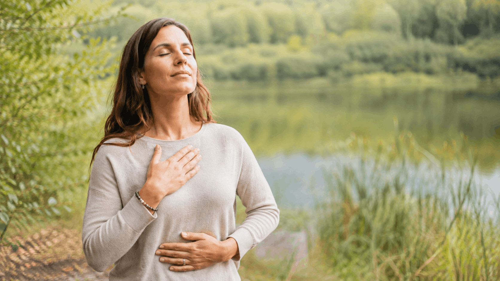 People Pleasing – bewusste Atempause mit Händen auf Brust und Bauch in der Natur
