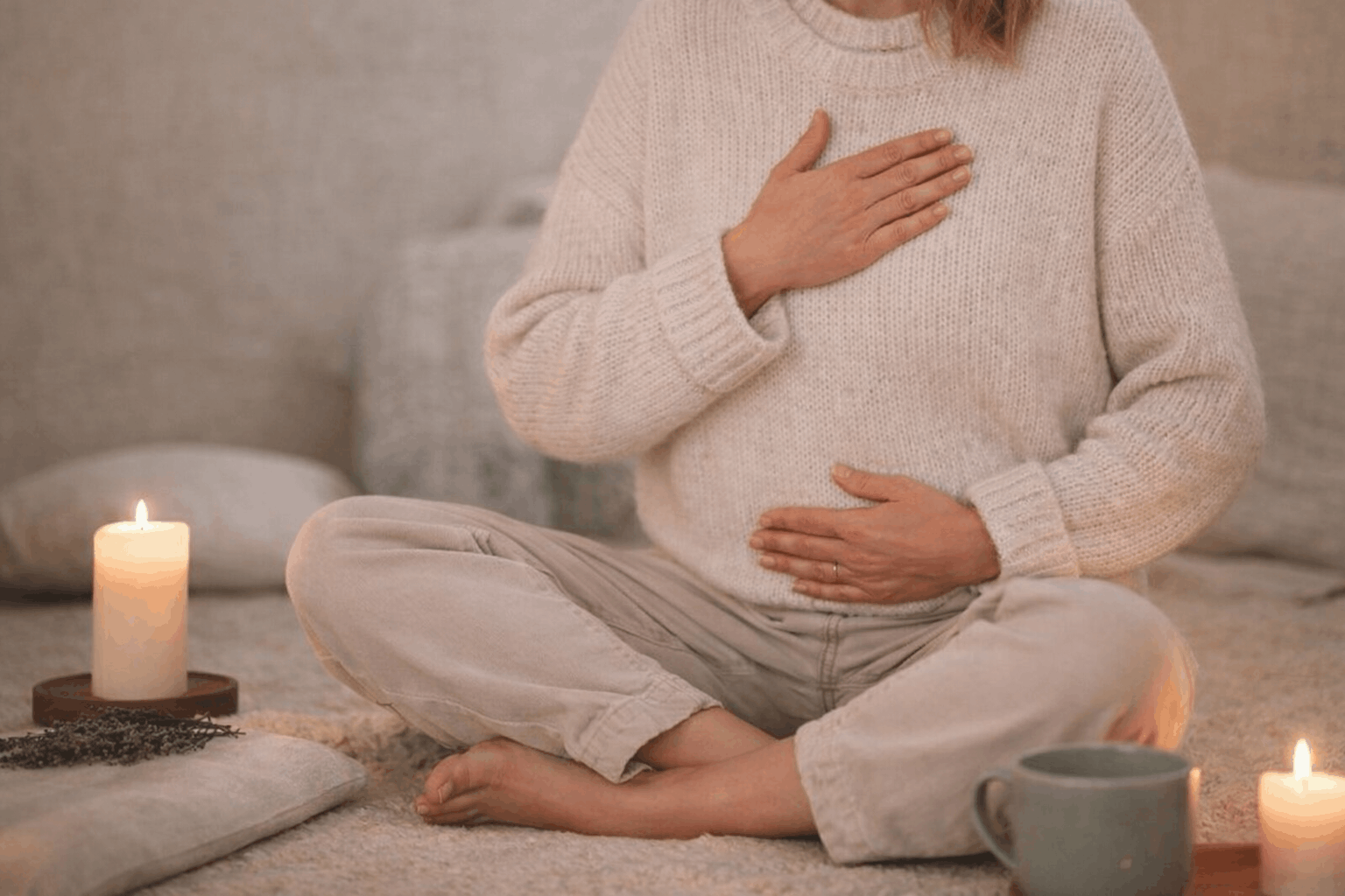 Frau sitzt entspannt mit Hand auf dem Bauch im warmen Licht und beruhigt ihr Nervensystem bei Reizdarm Beschwerden
