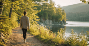 Frau spaziert auf einem Waldweg am See in der Natur, um Stress abzubauen und das Nervensystem zu beruhigen.